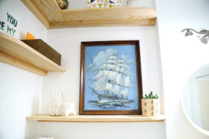 Close up of DIY shelves with framed artwork of ship.
