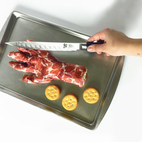 Halloween Severed Hand Cheese Ball appetizer with a hand holding a knife.